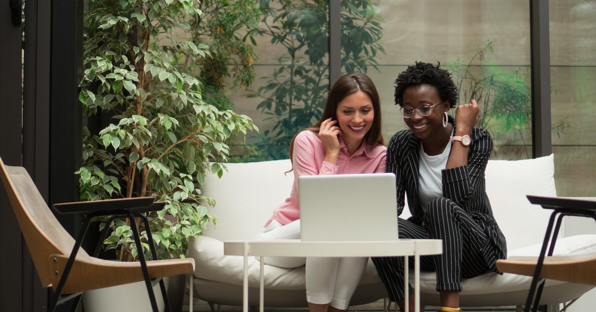 a couple of women sitting on a couch with a laptop