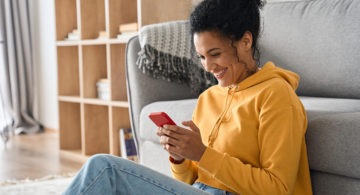 a person sitting on a couch and using a red phone