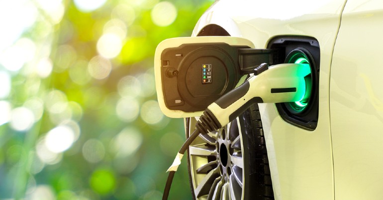 White electric vehicle plugged into its charger with blurred background