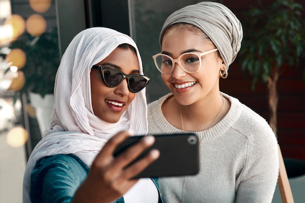 Two woman posing for a photo with their smart phone