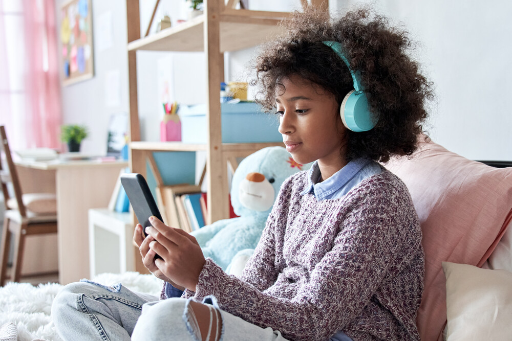 Young girl seating at home and playing with a few smart electronic devices