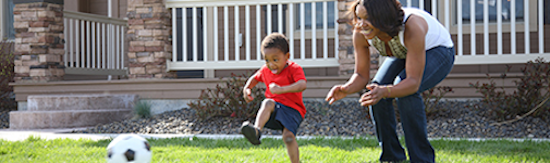 Mom and son playing with a soccer ball outside their house